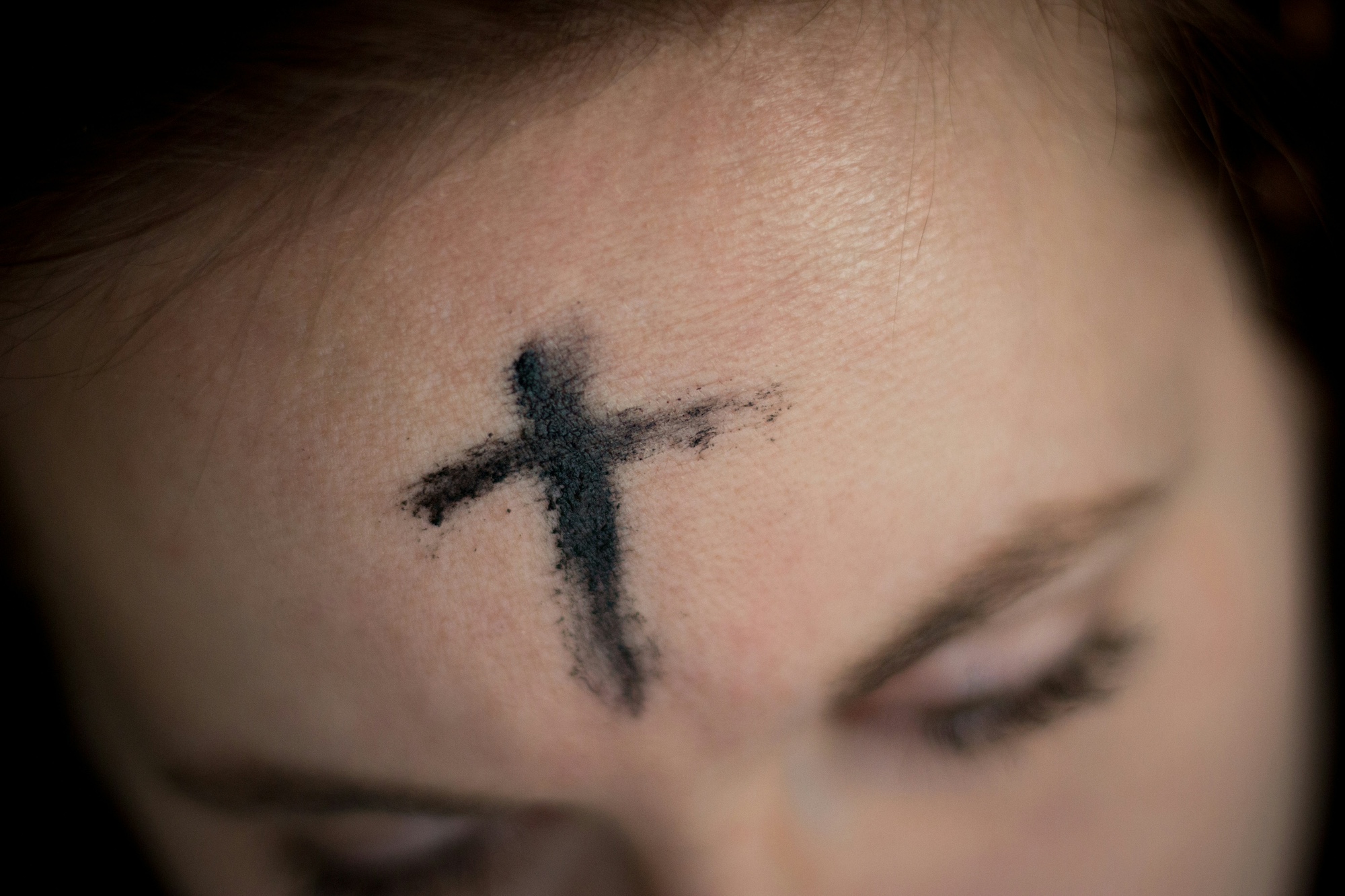 Photo du haut du visage d'une femme avec une croix dessinée à la cendre sur le front